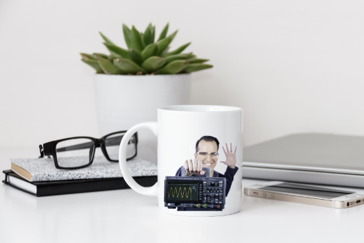 mug sitting on a desk with a person holding an oscilloscope on it