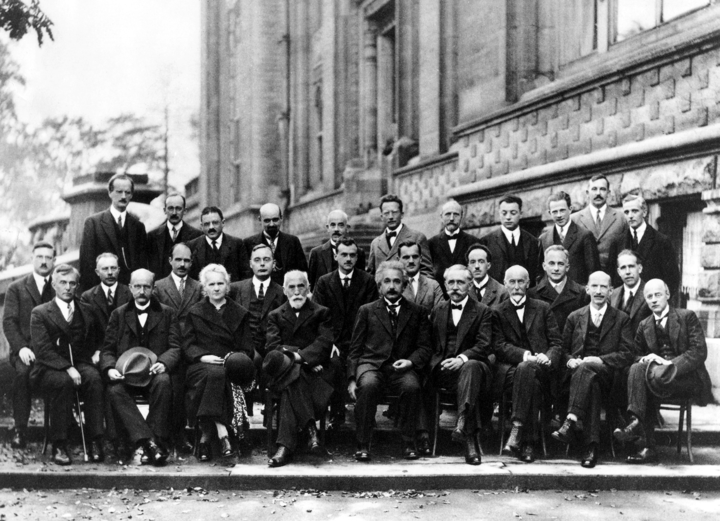 Solvay-Konferenz über Quantenmechanik 1927. Foto von Benjamin Couprie, Institut International de Physique Solvay, Brüssel, Belgien. Von hinten nach vorne und von links nach rechts:  Auguste Piccard, Émile Henriot, Paul Ehrenfest, Édouard Herzen, Théophile de Donder, Erwin Schrödinger, Jules-Émile Verschaffelt, Wolfgang Pauli, Werner Heisenberg, Ralph Howard Fowler, Léon Brillouin, Peter Debye, Martin Knudsen, William Lawrence Bragg, Hendrik Anthony Kramers, Paul Dirac, Arthur Compton, Louis de Broglie, Max Born, Niels Bohr, Irving Langmuir, Max Planck, Marie Skłodowska Curie, Hendrik Lorentz, Albert Einstein, Paul Langevin, Charles-Eugène Guye, Charles Thomson Rees Wilson, Owen Willans Richardson